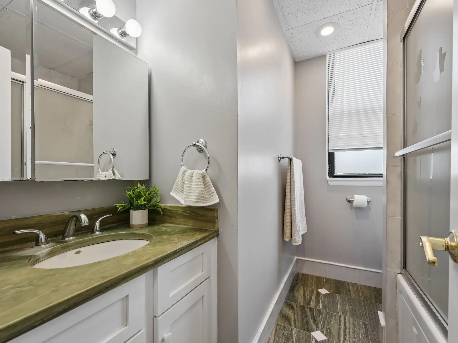 Full bathroom with green granite vanity, large mirror, tub-shower combination, and natural light at 124 East Main apartment