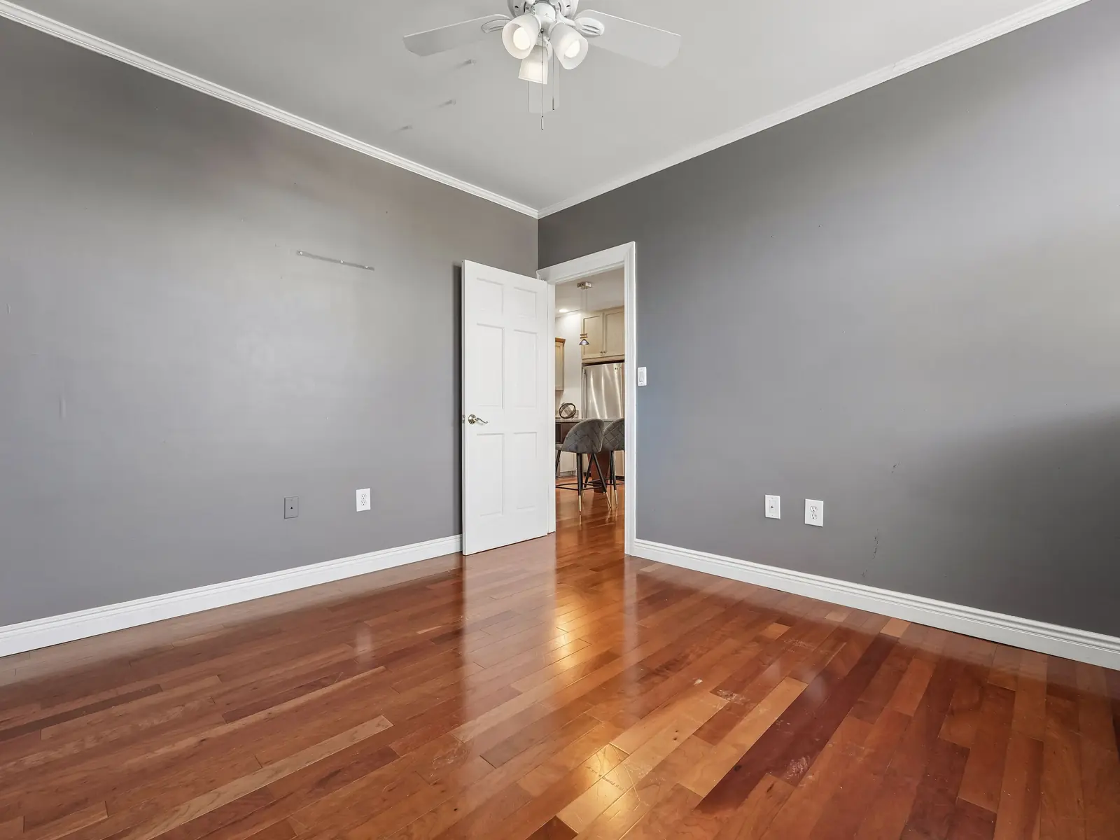 Second bedroom with gray walls, hardwood floors, and ceiling fan opening to the main living areas of the Denville apartment