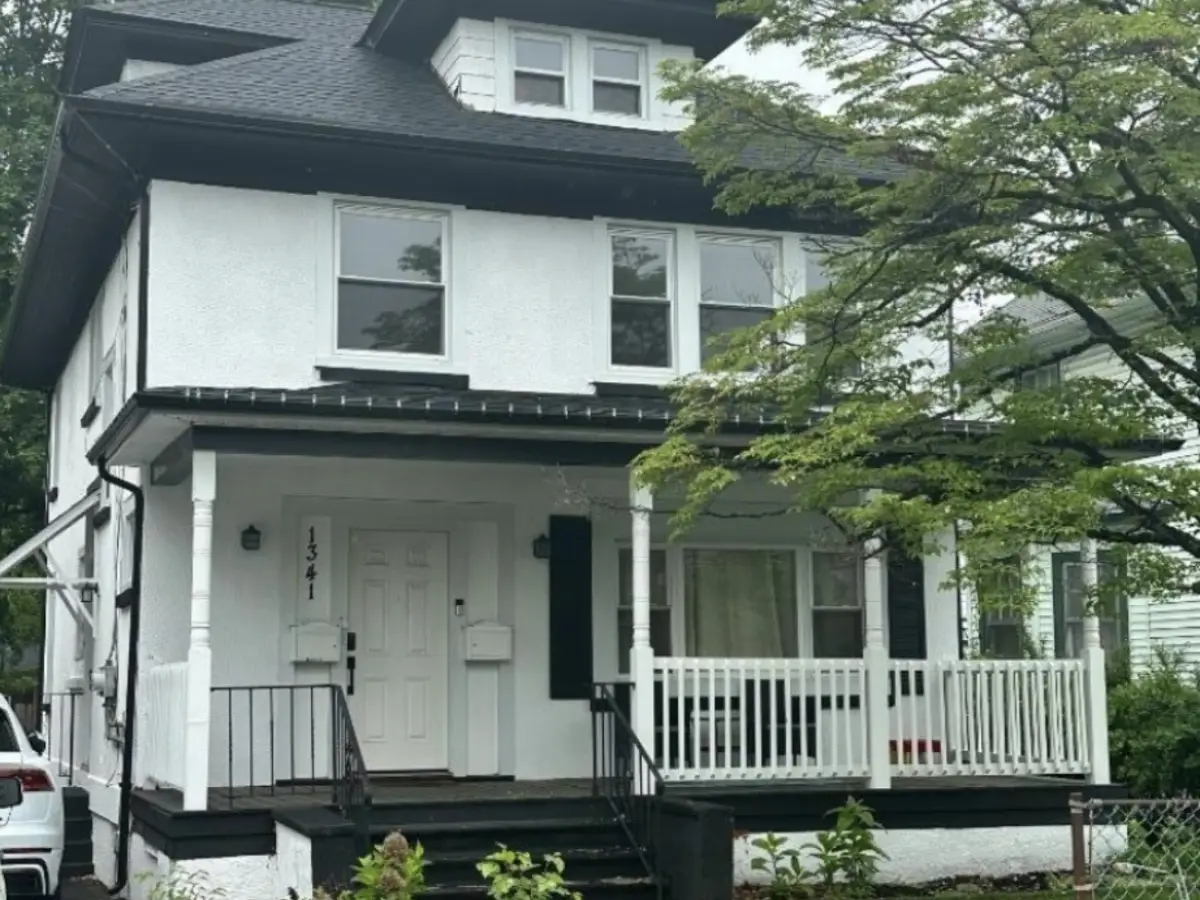 1341 East 2nd Street, Plainfield NJ — historic 1921 two-family home with white stucco facade, black trim, and covered front porch. BB listed and rented the renovated 2nd-floor apartment at full $2,700/month asking price.