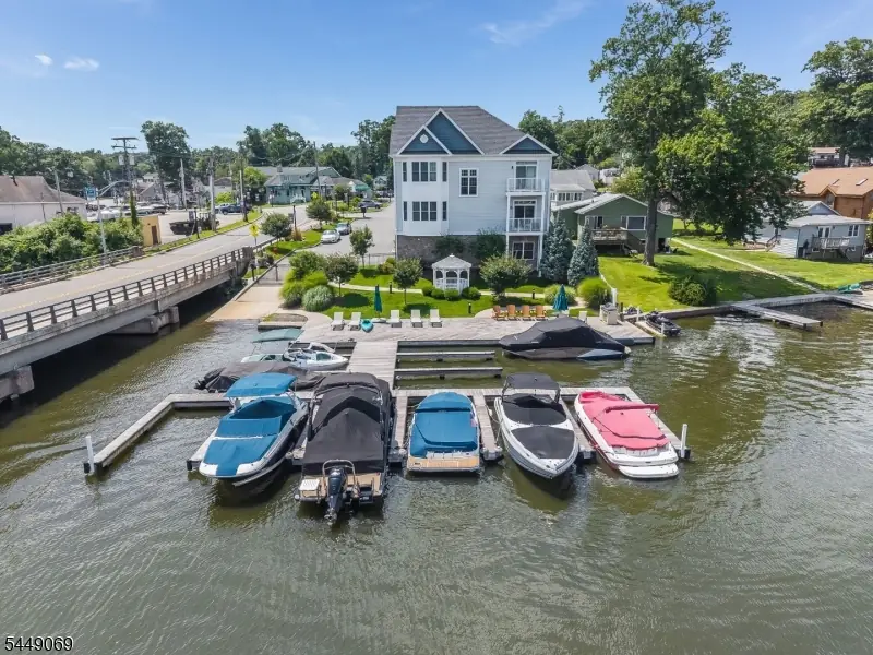 Aerial view of the community's private boat dock on Lake Hopatcong, a row of powerboats moored along the pier with the paver patio and lawn behind at 468 River Styx Road