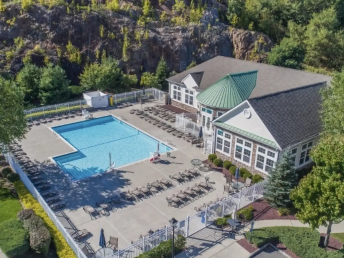 7210 Coventry Court, Riverdale NJ — aerial view of The Grande at Riverdale clubhouse with outdoor pool, lounge chairs, and patio set against a mountain rock backdrop. BB represented the tenant who rented this 2nd-floor Kerria-model condo at $2,800/month.